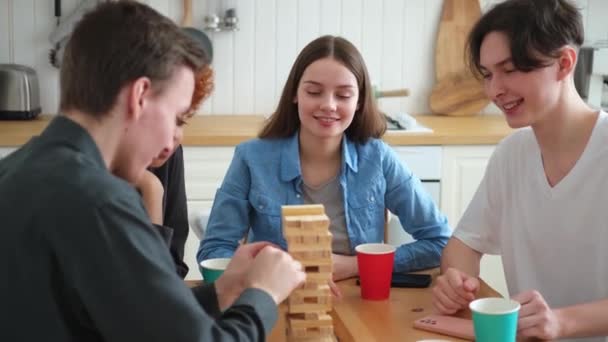 ホームパーティー 友達と一緒にボードゲームで遊ぶ時間を過ごす自宅で木製の塔をクラッシュします 屋内で一緒に楽しむ幸せな多様なグループ 混合レースの若い仲間最高の友人は週末を楽しんで — ストック動画