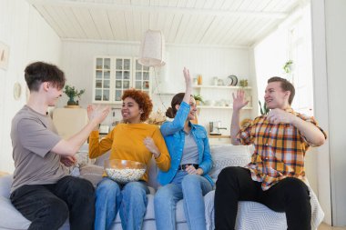 Bir grup arkadaş televizyonda futbol maçı izliyorlar. Memlekette zaferi kutlayan futbol taraftarları. Arkadaşlık sporu eğlence konsepti. Çeşitli arkadaşlar evde birlikte eğleniyorlar.