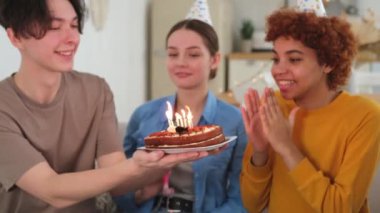 Bir dilek tut. Parti şapkası takan bir kadın doğum günü pastasında yanan mumları üflüyor. Doğum günün kutlu olsun. Bir grup arkadaş kızın doğum gününü kutluyor. İnsanlar doğum gününü evde partiyle kutluyor.