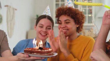 Bir dilek tut. Parti şapkası takan bir kadın doğum günü pastasında yanan mumları üflüyor. Doğum günün kutlu olsun. Bir grup arkadaş kızın doğum gününü kutluyor. İnsanlar doğum gününü evde partiyle kutluyor.