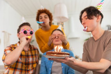 Bir dilek tut. Parti şapkası takan bir kadın doğum günü pastasında yanan mumları üflüyor. Doğum günün kutlu olsun. Bir grup arkadaş kızın doğum gününü kutluyor. İnsanlar doğum gününü evde partiyle kutluyor.