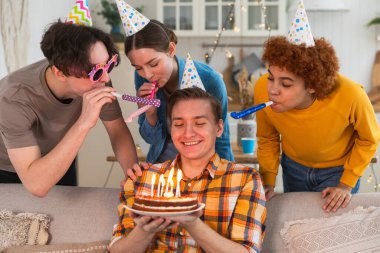 Bir dilek tut. Parti şapkası takmış bir adam doğum günü pastasında yanan mumları üflüyor. Doğum günün kutlu olsun. Arkadaş grubu adama mutlu yıllar diliyor. İnsanlar doğum gününü evde partiyle kutluyor.