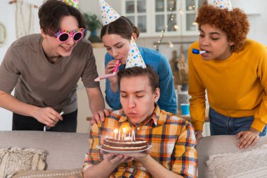 Bir dilek tut. Parti şapkası takmış bir adam doğum günü pastasında yanan mumları üflüyor. Doğum günün kutlu olsun. Arkadaş grubu adama mutlu yıllar diliyor. İnsanlar doğum gününü evde partiyle kutluyor.