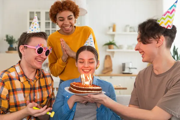 願い事をする 誕生日のケーキにろうそくを吹き飛ばすパーティーキャップを着ている女性 ハッピーバースデーパーティー 友人のグループは 少女の幸せな誕生日を願っています 自宅でパーティーで誕生日を祝う人 — ストック写真