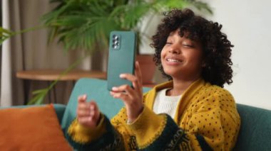 African American girl holding smartphone having video chat. Female blogger chatting with best friends in social network. Young woman having virtual meeting online chat video call at home