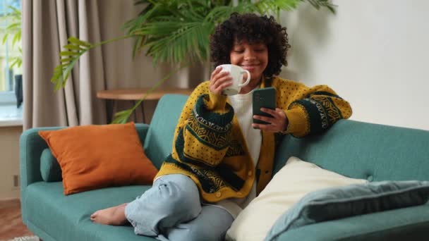 Good Morning African Girl Drinking Coffee Holding Smartphone Sitting Couch — Stock Video