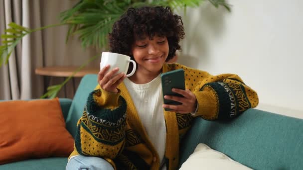 Dobré Ráno Africká Dívka Pije Kávu Drží Smartphone Sedí Gauči — Stock video