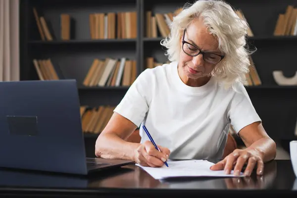 Старшая Женщина Средних Лет Использует Ноутбук Писать Заметки Рабочем Месте Лицензионные Стоковые Изображения