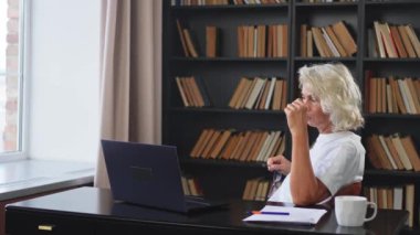 Görüntülü arama. Orta yaşlı mutlu bir kadın dizüstü bilgisayarla oturup video görüşmesi yapıyor. Olgun yaşlı bayan internette konuşarak eğleniyor. Eski nesil modern teknoloji kullanımı Sanal toplantı çevrimiçi sohbet