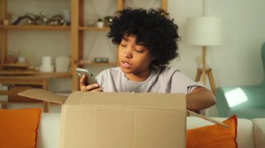 Mutsuz kızgın Afrikalı kadın posta servisinde arızalı nakliye hatasıyla gelen kutuyu açıyor. Sinirli müşteri istemcisi akıllı telefondan yanlış paket kontrolü uygulaması alıyor