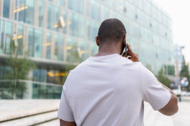 Arkaya bakan Afro-Amerikan adam dışarıda akıllı telefondan konuşuyor. Şehirde cep telefonu olan tanınmayan bir adam sokakta yürüyor. Cep telefonuyla cevap veren adam cep telefonuyla konuşuyor.