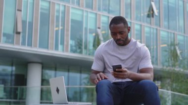 Şehirdeki bir sokakta dizüstü bilgisayar kullanarak konuşan Afro-Amerikalı bir adam. İş adamı sanal toplantı yapıyor. Uzman programcı dışarıda çalışan bir telefon bilgisayarı kullanıyor. Uzak çalışma