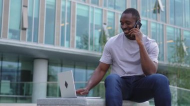 Şehirdeki bir sokakta dizüstü bilgisayar kullanarak konuşan Afro-Amerikalı bir adam. İş adamı sanal toplantı yapıyor. Uzman programcı dışarıda çalışan bir telefon bilgisayarı kullanıyor. Uzak çalışma