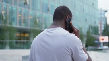 Arkaya bakan Afro-Amerikan adam dışarıda akıllı telefondan konuşuyor. Şehirde cep telefonu olan tanınmayan bir adam sokakta yürüyor. Cep telefonuyla cevap veren adam cep telefonuyla konuşuyor.