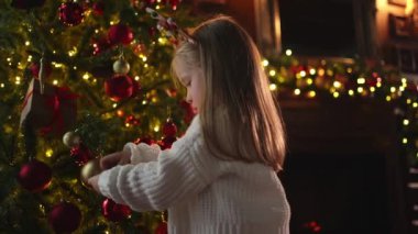 Mutlu Noeller Noel tatili. Noel arifesinde evde Noel ağacı süsleyen küçük bir kız. Klasik Noel ağacının yanında, elinde kış süsleri olan genç bir çocuk. Noel 'i kutlama zamanı.