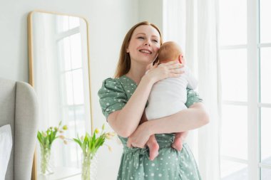 Evde mutlu bir aile. Anne kucağında küçük bir kız çocuğu. Anne ve bebek evde birlikte oynayarak rahatlar. Anne bebeğe sevgiyle sarılır. Bebeği emziren anne.