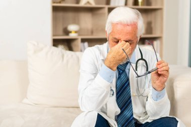 Üzgün, yaşlı, hastane ya da doktor ofisinde üniformalı bir erkek doktor. Mutsuz bir pratisyen hekim, klinikte profesyonel sağlık uzmanı. Sağlık hizmetleri kavramı