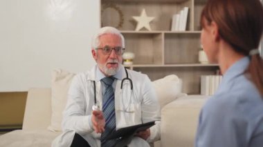 Kıdemli doktor, genç bayanı doktor muayenehanesinde ya da evde muayene ediyor. Kız hasta ve doktorun hastane odasında muayenesi var. Tıbbi sağlık hizmetleri sağlık kontrolü. Doktoru ziyaret et.