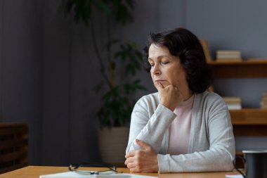 Üzgün, hasta, yalnız, yaşlı bir kadın evde yalnız oturuyor. Mutsuz, olgun bir büyükanne yas tutuyor. Ölümüne kötü haber. Stresli yaşlı kadın yalnızlıktan muzdarip.