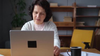 Yaşlı kadın tapınaklara dokunuyor ve stres yaşıyor. Dizüstü bilgisayarla çalışmaktan bıkmış, baş ağrısı çeken şakakların alnına sürtünmekten bıkmış bir kadın. Uzun dizüstü bilgisayar kullanımı görme sendromu yorgunluğu