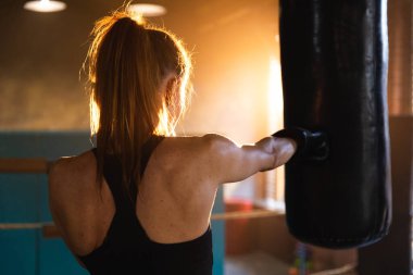 Kadın kendini savunma gücü. Güçlü kadın boks ringinde boks antrenmanı yapıyor. Sağlıklı, boks torbası yumruklayan güçlü bir kız. Boks salonunda antrenman günü. Vücut çalıştırma eğitimine uygun güç