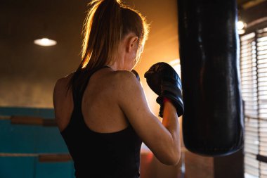 Kadın kendini savunma gücü. Güçlü kadın boks ringinde boks antrenmanı yapıyor. Sağlıklı, boks torbası yumruklayan güçlü bir kız. Boks salonunda antrenman günü. Vücut çalıştırma eğitimine uygun güç