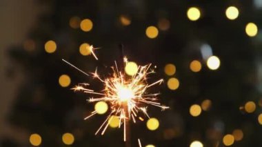 Noel ağacı arka planında parlak maytap mumları yanıyor. Xmas evde ışıklandırma dekorasyonu. Şenlik Büyüsü, tatil partisi için ışık yakıyor. Havai fişeklerle Noel arifesi
