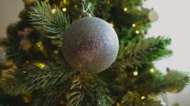 Mutlu Noeller Noel 'ler. Gümüş süsleme topu ve süslenmiş klasik Noel ağacının üzerindeki çelenk ışıkları. Gümüş süslemeli Noel ağacı. Evde Noel arifesi
