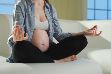 Hamilelik öncesi nefes alma. Hamile bir kadının koca göbeği, el ve çene hareketi. Nilüfer çiçekli hamile kız evde yoga farkındalığı meditasyonu yapıyor. Hamilelik sırasındaki rahatlama.