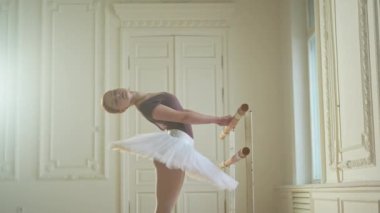 Tutu etekli genç balerin dans sınıfında bale pozisyonlarında dans ediyor. Dans stüdyosundaki genç klasik dansçı kadın. Bale sınıfı eğitim konsepti