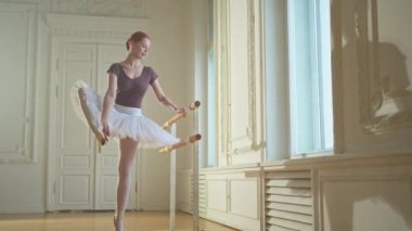 Tutu etekli genç balerin dans sınıfında bale pozisyonlarında dans ediyor. Dans stüdyosundaki genç klasik dansçı kadın. Bale sınıfı eğitim konsepti