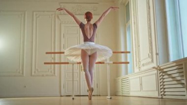 Tutu etekli genç balerin dans sınıfında bale pozisyonlarında dans ediyor. Dans stüdyosundaki genç klasik dansçı kadın. Bale sınıfı eğitim konsepti