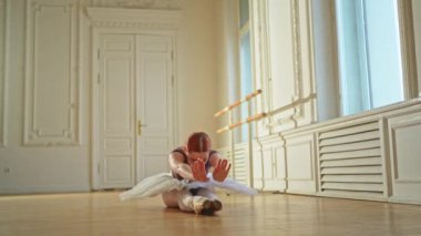 Tutu etekli genç balerin dans sınıfında bale pozisyonunda esneme hareketleri yapıyor. Dans stüdyosundaki genç klasik dansçı kadın. Bale sınıfı eğitim konsepti