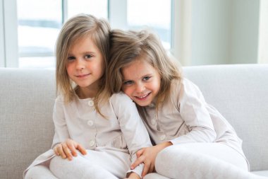 Mutlu aile kardeş sevgisi. İki komik ikiz kız kardeş, evde birlikte oynayarak sevgi dolu bir sevgiyle sarılıyorlar. Mutlu çocuk yaşam tarzı. Tek yumurta ikizi kızlar kucaklaşır. Kızlar arkadaşlık ve gençlik