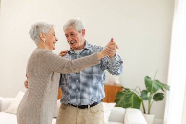 Yürümeye devam. Romantik olgun çift evde müzik eşliğinde dans ediyor. Mutlu gülümseyen aile emeklisi kadın koca eş birlikte eğleniyor. Aile zamanı aşk bakımı