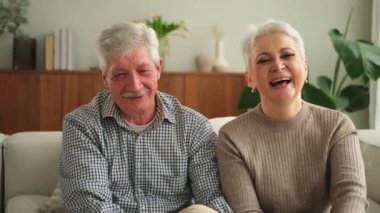 Yetişkin bir çift, evdeki kanepede oturup kameraya bakıyor. Orta yaşlı karı-koca portresi. Büyükannem ve büyükbabam birlikte. Aile zamanı sevgi ve ilgi