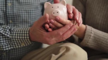 Gelecek için para yatırımı biriktiriyorum. Yaşlı yetişkin çift el sıkışıyor kumbarada para ile. Yaşlı kadın emeklilik bütçesinden tasarruf ediyor. Yatırım bankacılığı kavramı
