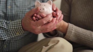 Gelecek için para yatırımı biriktiriyorum. Yaşlı yetişkin çift el sıkışıyor kumbarada para ile. Yaşlı kadın emeklilik bütçesinden tasarruf ediyor. Yatırım bankacılığı kavramı