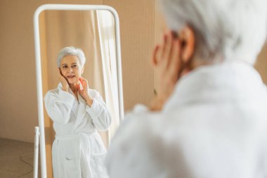 Love yourself. Beautiful old woman enjoying mirror reflection. Senior older lady spending morning in bathroom looking at mirror confident happy. Woman doing daily morning beauty routine. Self love clipart