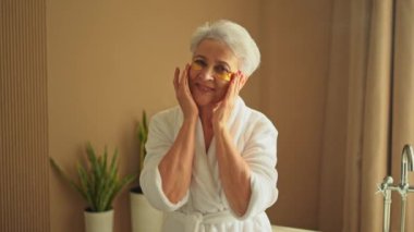 Göz bandı güzellik tedavisi. Kolajen pedleri altında yetişkin bir kadın. Göz altı yamalı yaşlı kadın yüz bakımı yaptırıyor. Son sınıftaki bayan banyoda dinleniyor.