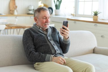 Arkadaşlarıyla video görüşmesinde orta yaşlı adam sohbetin kutlu olsun. Yaşlı, olgun büyükbabaya gülüp yetişkin çocuklarla internette konuşarak eğleniyor. Eski nesil modern teknoloji kullanımı