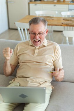 Üst düzey adam internetten alışveriş yapıyor. Kredi kartıyla ödeme yapıyor. Yaşlı büyükbaba internetten satın alıyor kredi kartı bilgilerini gir. Çevrimiçi alışveriş teslimat servisi. Eski nesil modern teknoloji kullanımı
