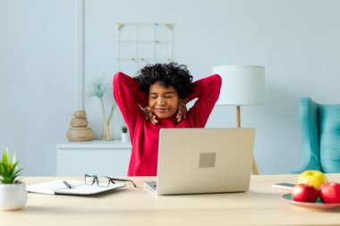 Ofisteki Afrikalı Amerikalı kız ellerini ve vücudunu dinlendirip laptopta işe ara veriyor. Neşeli genç kadın serbest çalışan iş kadını iyi sonuçtan tatmin olan işten sonra mutlu.