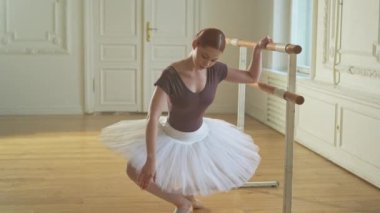 Tutu etekli genç balerin dans sınıfında bale pozisyonlarında dans ediyor. Dans stüdyosundaki genç klasik dansçı kadın. Bale sınıfı eğitim konsepti