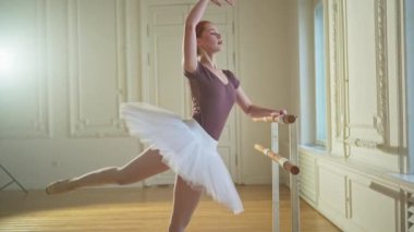 Tutu etekli genç balerin dans sınıfında bale pozisyonlarında dans ediyor. Dans stüdyosundaki genç klasik dansçı kadın. Bale sınıfı eğitim konsepti