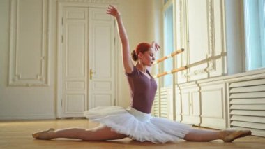 Tutu etekli genç balerin dans sınıfında bale pozisyonunda esneme hareketleri yapıyor. Dans stüdyosundaki genç klasik dansçı kadın. Bale sınıfı eğitim konsepti