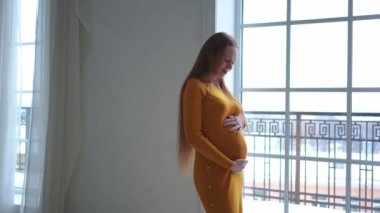 Hamilelik anneliği insanların gelecek beklentisi. Evinin penceresinin yanında koca göbekli hamile bir kadın var. Karnına sarılan ve hamileliğin tadını çıkaran bir kız. Annelik şefkati ebeveynlik yeni yaşam konsepti