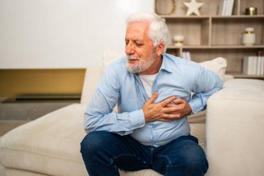 Kalp krizi, kalp krizi. Memnuniyetsiz orta yaşlı adam göğüs ağrısı çekiyor kalp krizi geçiriyor evde sağlık sorunları var. Yaşlı büyükbaba göğsüne dokunuyor ve damar tıkanıklığı yaşıyor.