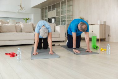 Fitness eğitimi. Yaşlı, sağlıklı, formda bir çift evde spor yapıyor. Orta yaşlı eş antrenman yapıyor. Sağlık hizmetleri sağlıklı yaşam tarzı. Yaşlı adam için egzersiz rehabilitasyonu