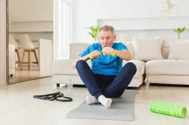 Fitness antrenmanı. Üst düzey boksör dambılları kaldırıyor. Yetişkin, sağlıklı bir adam evde spor yapıyor. Büyükbabanın rehabilitasyonu var. Sağlık hizmetleri